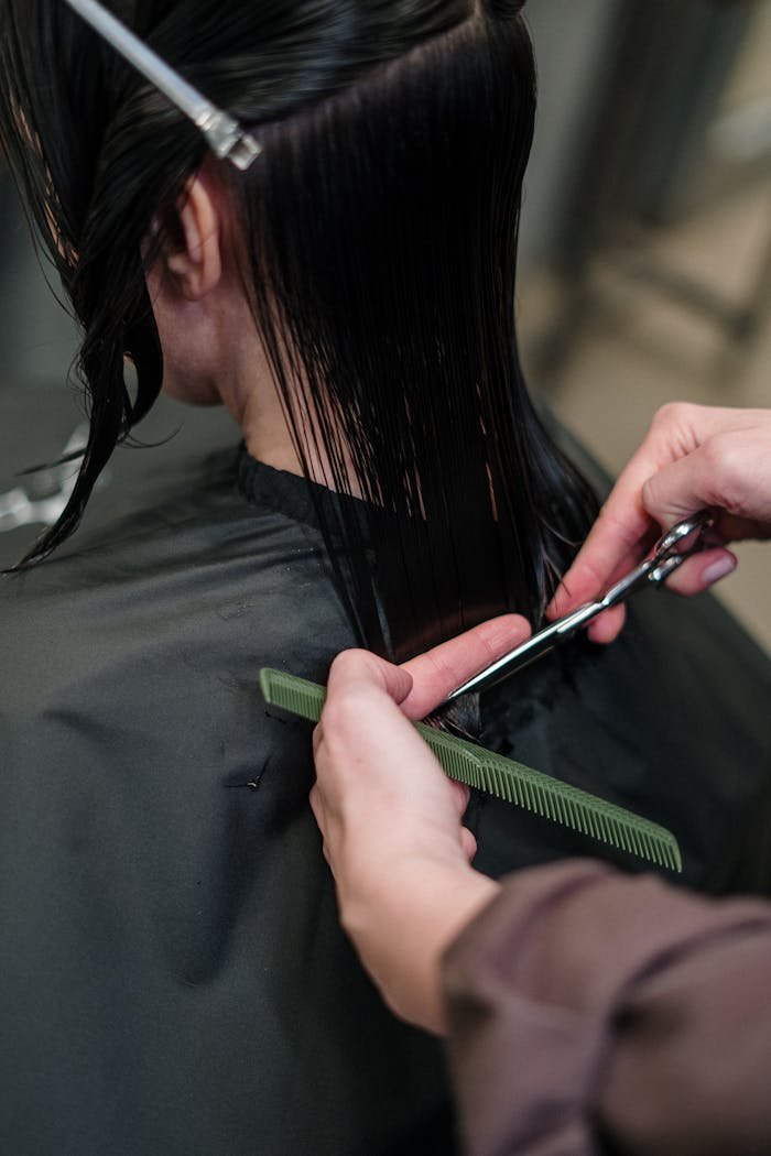 Close-up of a hairstylist cutting a woman's hair in a salon, showcasing precise techniques.